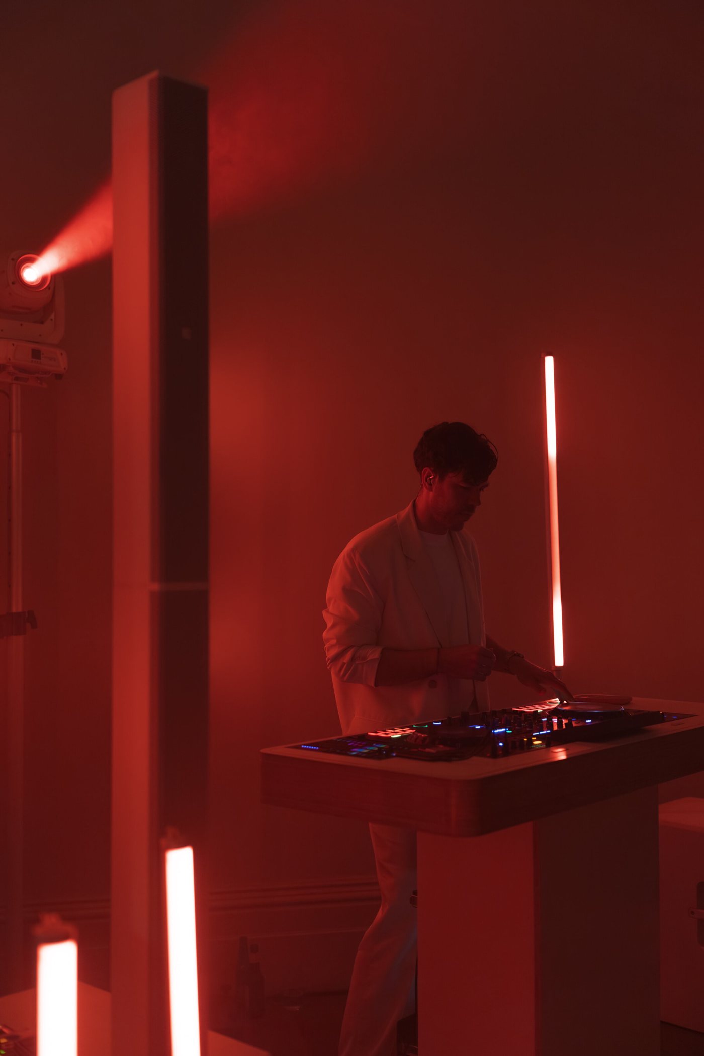 Josh Parish, founder of Married to the Groove, DJing in a white suit under red tube lighting
