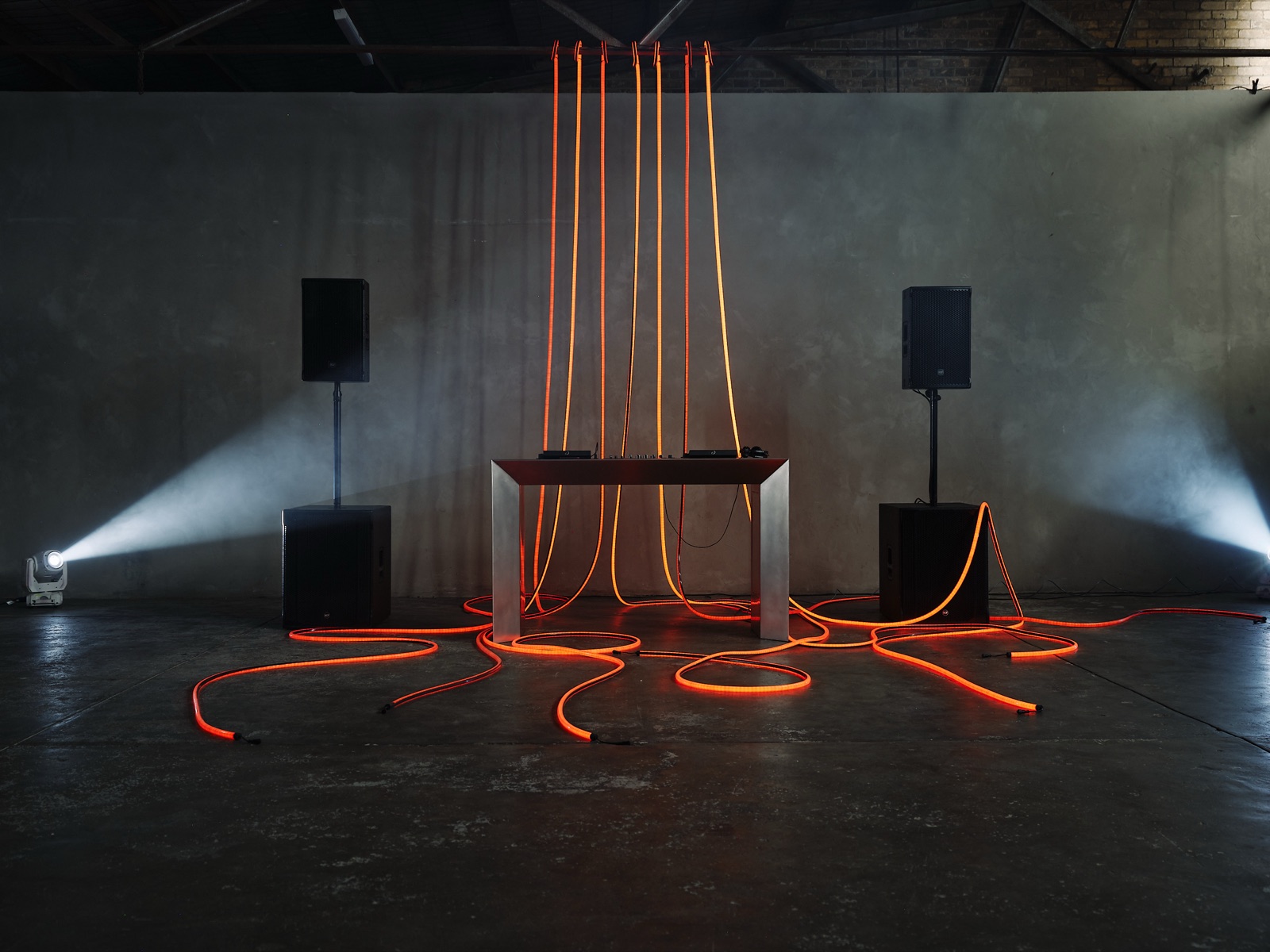 The full look: stainless steel table, black speakers, rope lighting, moving heads and haze